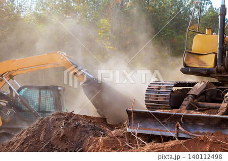 Heavy machinery removes soil debris at construction site preparing area for upcoming work 140112498