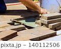 Worker is carefully placing bricks on surface while using trowel to apply mortar 140112506
