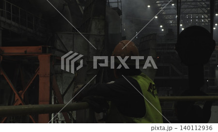 Nighttime Safety Supervisor In Protective Attire Oversees Complex Manufacturing Equipment Operations . Stock clip 140112936