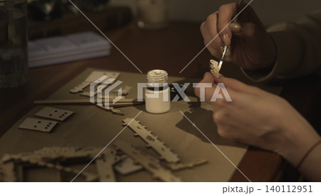 Artisan Meticulously Attaching Lasercut Wooden Parts With Adhesive In Cozy Workshop Setting. Media Artisan Meticulously Attaching Lasercut Wooden Parts With Adhesive In Cozy Workshop Setting. Media 140112951