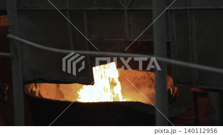 Molten Metal Pouring. Interior Of Glowing Furnace With Molten Metal Pouring Into Crucible From Ladle . Stock clip 140112956