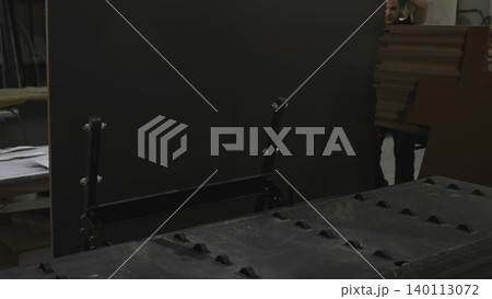 Workers Coordinate Effort To Place Heavy Black Panel Onto Loading Frame Near Conveyor System . Media Workers Coordinate Effort To Place Heavy Black Panel Onto Loading Frame Near Conveyor System . Media 140113072