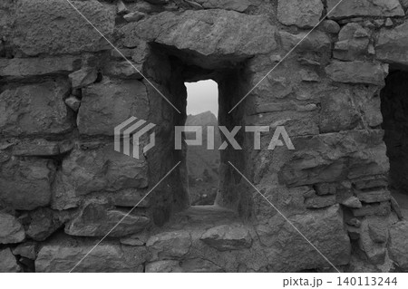 Stone arrow-hole close up with a mountain in the background in black and white. Stone arrow-hole close up with a mountain in the background in black and white. 140113244