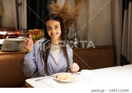 Woman smiling giving thumbs up eating meal Woman smiling giving thumbs up eating meal 140113290