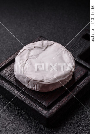 Pink Brie or Camembert cheese with honey, jam, figs, and crackers. Brie cheese 140113360
