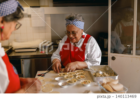 Happy senior Black woman preparing homemade food in a community kitchen for ageless vitality Happy senior Black woman preparing homemade food in a community kitchen for ageless vitality 140113469