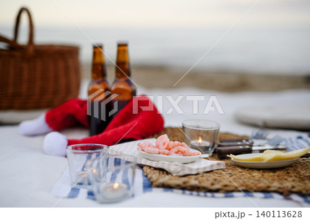 Beach picnic with schripms, beer, fruit and candles Beach picnic with schripms, beer, fruit and candles 140113628