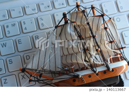 Wooden Sailing Ship Model Lies On White Computer Keyboard With Latin Characters Only 140113667