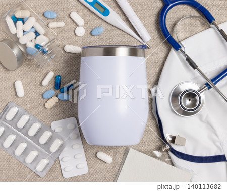White 12 oz tumbler mockup with medical accessories and scrub uniform top view, blank template White 12 oz tumbler mockup with medical accessories and scrub uniform top view, blank template 140113682