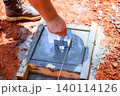 Worker uses tool to level freshly poured concrete at construction site 140114126