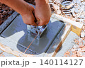 Construction worker secures metal anchor in fresh concrete at building site. 140114127
