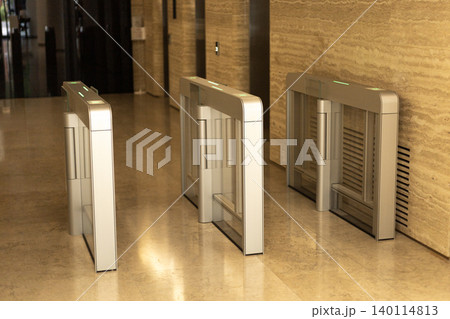 Electronic security turnstiles with glass panels in modern elevator lobby 140114813