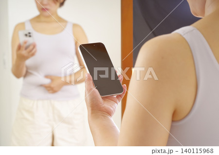 スマホで体型管理をする女性 140115968