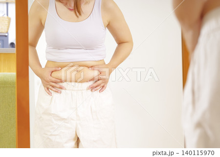 鏡の前でぽっこりお腹を気にする女性 鏡の前でぽっこりお腹を気にする女性 140115970