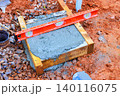 Workers pour concrete into wooden frame while using level tool to check surface 140116075