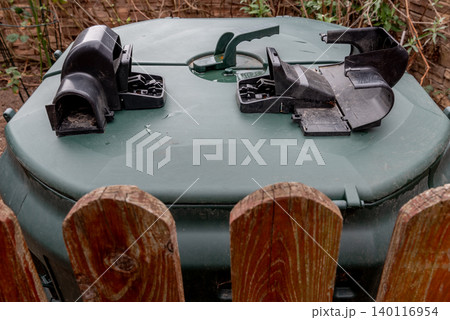 Outdoor compost bin with plastic rodent traps behind wooden fence Outdoor compost bin with plastic rodent traps behind wooden fence 140116954
