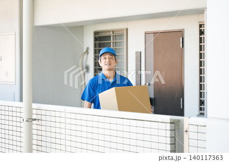 荷物を運ぶ作業服姿のシニア男性 140117363