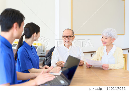 日本人シニアに説明をするアジア人介護士 140117951