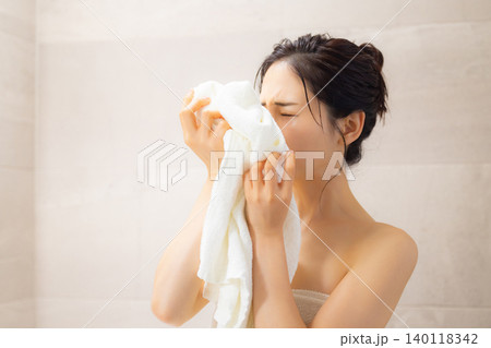 お風呂上がりに顔をタオルで拭く若い女性 お風呂上がりに顔をタオルで拭く若い女性 140118342