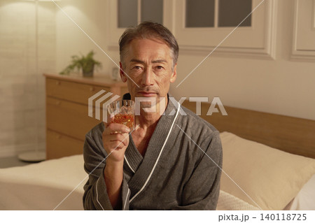 寝室でウイスキーを飲むシニア男性　ポートレート　カメラ目線 140118725