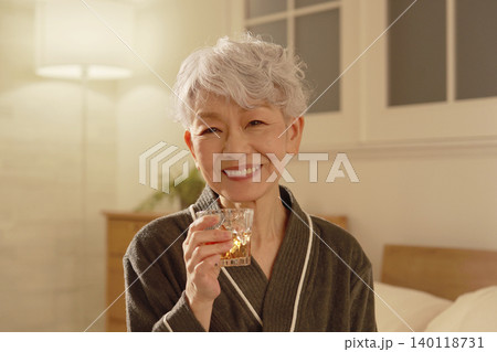 寝室でウイスキーを飲むシニア女性　ポートレート　カメラ目線 140118731