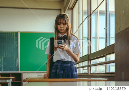 教室でスマホを見る女子高生 140118879