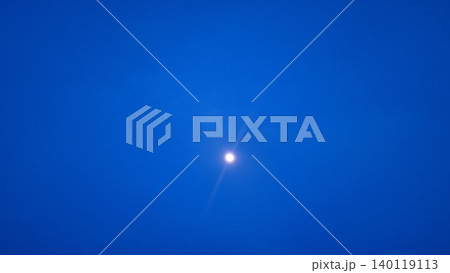 Real photograph of the moon shining in a deep blue evening sky with a calm minimalist atmosphere. 140119113