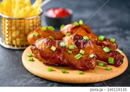 Grilled chicken drumsticks with ketchup and french fry on a black table. 140119130