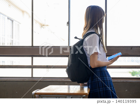 窓辺でスマホを持つ女子高生 140119395