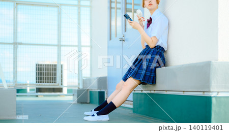 制服姿でスマホを操作する少女 140119401