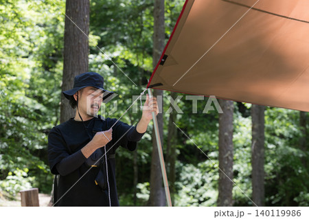 森林でタープを張る準備を楽しむ男性と自然体験のアウトドアイメージクローズアップ 140119986