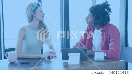 Discussing woman in sleeveless top and man in red shirt reviewing tablet papers at cafe Discussing woman in sleeveless top and man in red shirt reviewing tablet papers at cafe 140121418