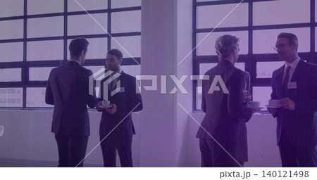 Holding white cups, group wearing suits networking near grid windows with name badges 140121498