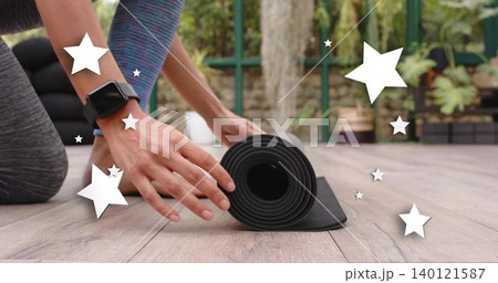 Rolling hands and forearms guiding black yoga mat on wooden deck, showing smartwatch and leggings Rolling hands and forearms guiding black yoga mat on wooden deck, showing smartwatch and leggings 140121587