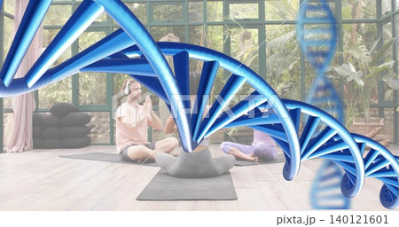 Meditating three adults wearing athletic clothes on yoga mats in glass sunroom, blue DNA overlaying Meditating three adults wearing athletic clothes on yoga mats in glass sunroom, blue DNA overlaying 140121601