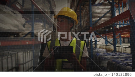 Inspecting warehouse worker holding tablet in aisle, wearing yellow hard hat and hi-vis vest, HUD Inspecting warehouse worker holding tablet in aisle, wearing yellow hard hat and hi-vis vest, HUD 140121896