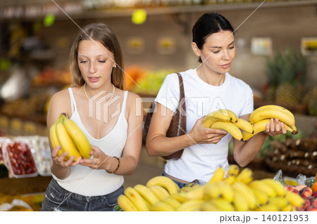 Two women shopping in vegetable store and buy banana 140121953
