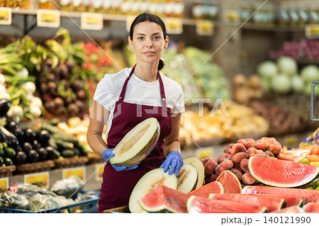 Adult woman seller putting melon in vegetable shop Adult woman seller putting melon in vegetable shop 140121990