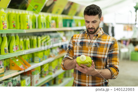 Adult man choosing fertilizers at garden center Adult man choosing fertilizers at garden center 140122003