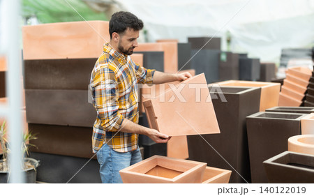 Man chooses large flower pot-tub in shop Man chooses large flower pot-tub in shop 140122019