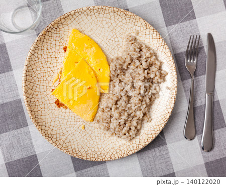 Boiled pearl barley with omelette served on dish on checkered cloth Boiled pearl barley with omelette served on dish on checkered cloth 140122020