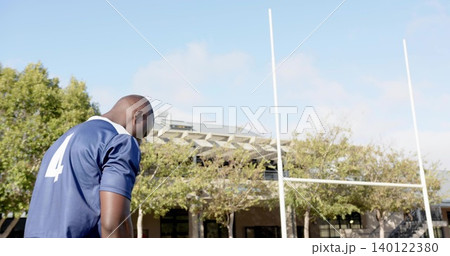 Standing athlete wearing dark blue jersey number 4 with sports shorts near white posts, copy space Standing athlete wearing dark blue jersey number 4 with sports shorts near white posts, copy space 140122380