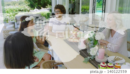 Gathering five women, one wearing sash and headband, chatting at wooden patio table with cupcakes Gathering five women, one wearing sash and headband, chatting at wooden patio table with cupcakes 140122559