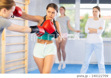 Women in boxing gloves punch deliver blow each other during training sparring session Women in boxing gloves punch deliver blow each other during training sparring session 140122709