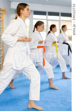 Team of teenage girls in kimonos uses new fighting techniques during karate lessons in gym 140122710