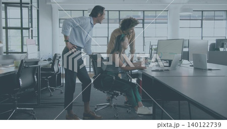 Collaborating team leaning around desk in open office, woman in tank top viewing monitor charts 140122739
