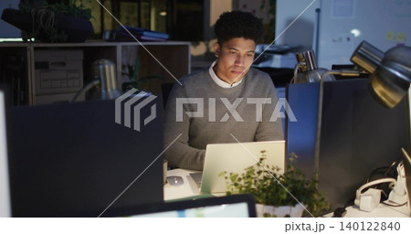 Working office worker in gray sweater white shirt, focusing on laptop in evening with lamp screens Working office worker in gray sweater white shirt, focusing on laptop in evening with lamp screens 140122840