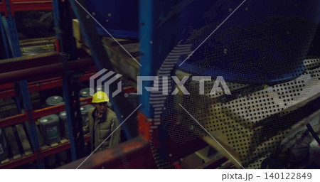 Inspecting worker wearing yellow hard hat, khaki vest scanning racks in storage, drums, copy space Inspecting worker wearing yellow hard hat, khaki vest scanning racks in storage, drums, copy space 140122849