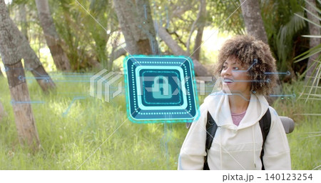 Standing woman wearing hoodie, backpack with rolled mat in sunlit grove, holo padlock, copy space Standing woman wearing hoodie, backpack with rolled mat in sunlit grove, holo padlock, copy space 140123254