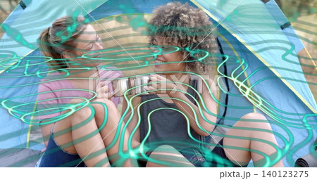 Passing two friends in shorts sharing camping mug inside blue-yellow dome tent, teal overlay Passing two friends in shorts sharing camping mug inside blue-yellow dome tent, teal overlay 140123275
